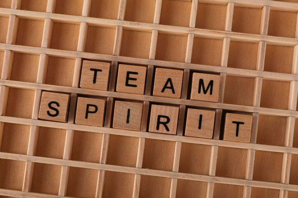 Wooden Scrabble tiles arranged to spell 'Team Spirit' on a wooden grid.